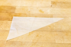 Die Herstellung eines Papierspritzbeutels. Zuerst ein Dreieck schneiden